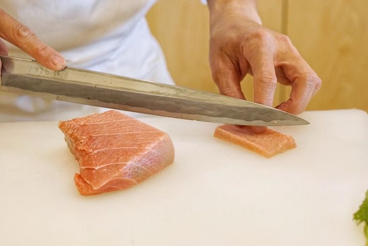 A chef slicing toro with a long knife