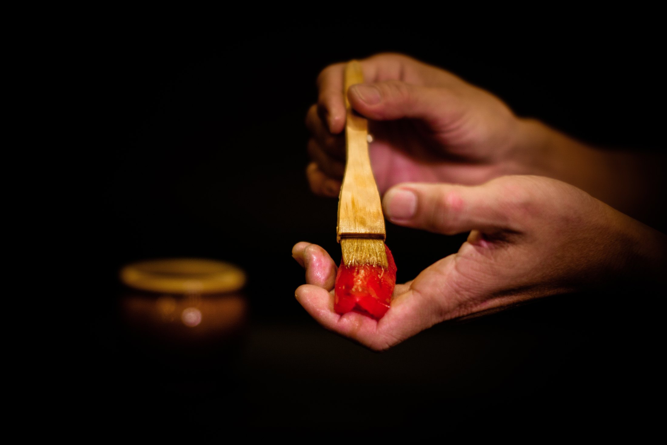 A chef brushing nitsume onto a piece of sushi at the Kazumasa counter